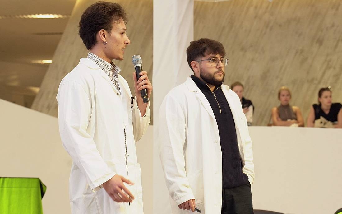 Zwei Personen in Laborkitteln sprechen auf einer Präsentation