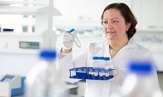 Dame in Labor schaut sich Flüssigkeiten in Reagenzbehältern an