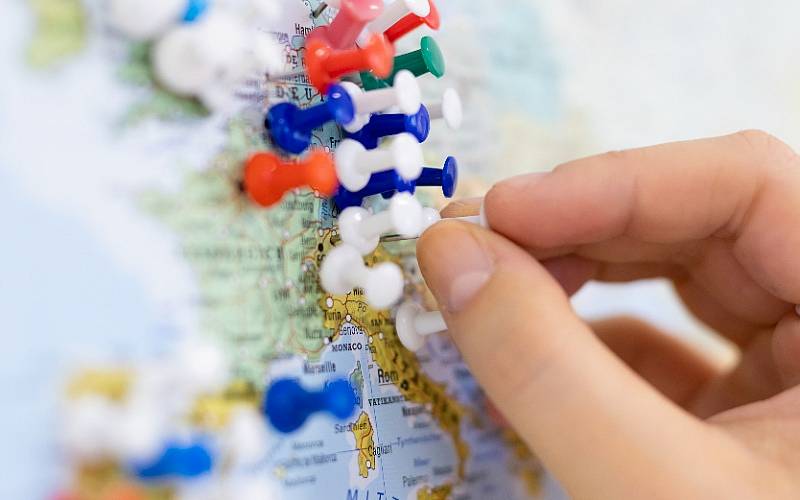 Eine Stecknadel wird auf eine Landkarte platziert