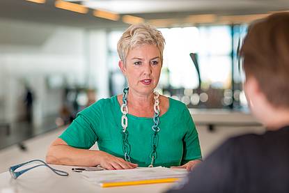 Dame mit kurzen blonden Haaren und Halskette in grünem Shirt