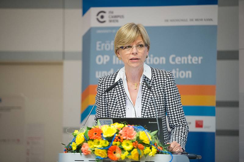 Dame mit kurzen blonden Haaren und Brille an Rednerpult mit Blumenbouquet im Vordergrund