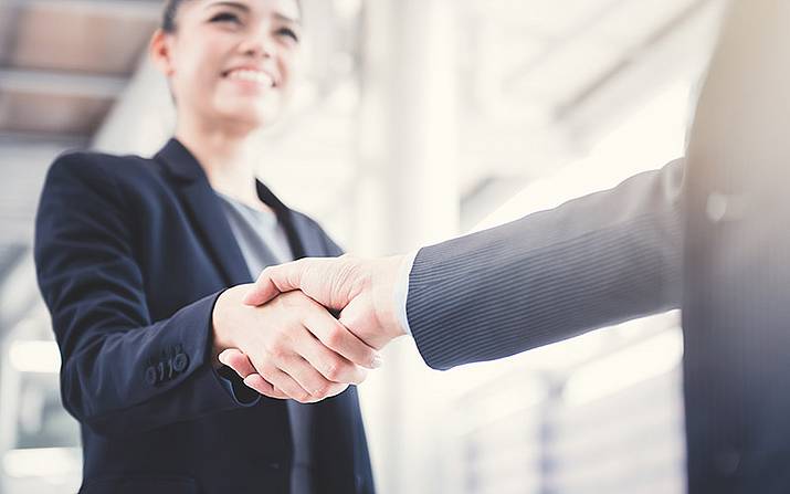 © Atstock Productions-shutterstock Zwei Personen schütteln einander lächelnd die Hände