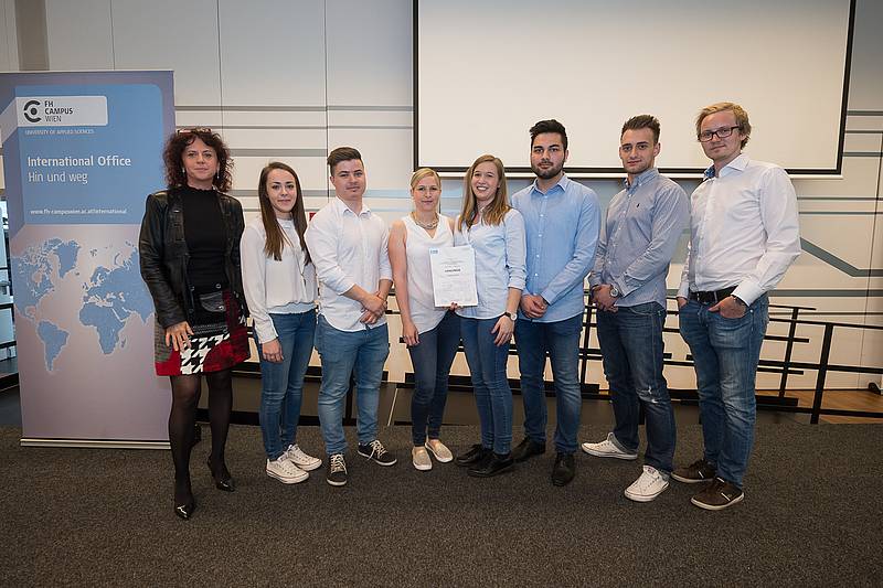 Gruppenbild mit acht Personen vor weißer Leinwand