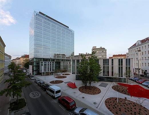 Ein hoher Neubau mit einer Flächendeckenden Glas Fassade ist abgebildet.