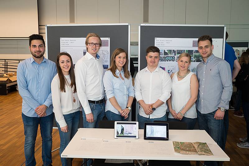 Gruppenfoto mit sieben Personen, die hinter einem Tisch stehen