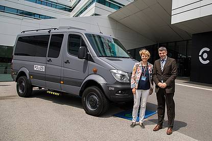 Dame und Herr stehen neben grauem Polizeibus vor dem Hochschule Campus Wien Hauptgebäude
