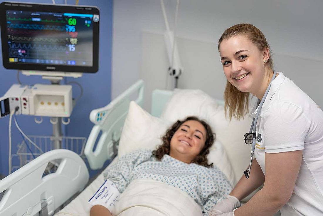 © HCW / Schedl Eine Pflegekraft neben einer Patient*in im Pflegebett