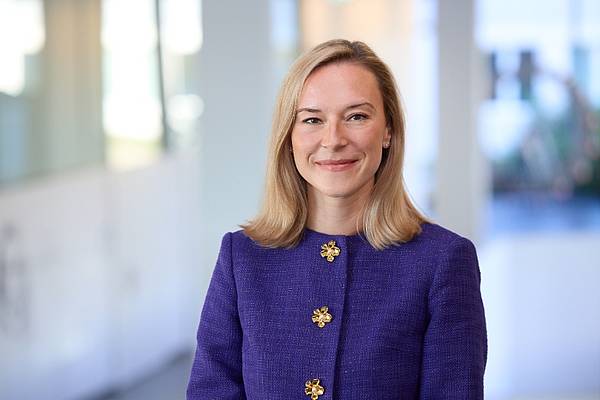 Portraitfoto einer blonden Frau vor verschwommenem Hintergrund