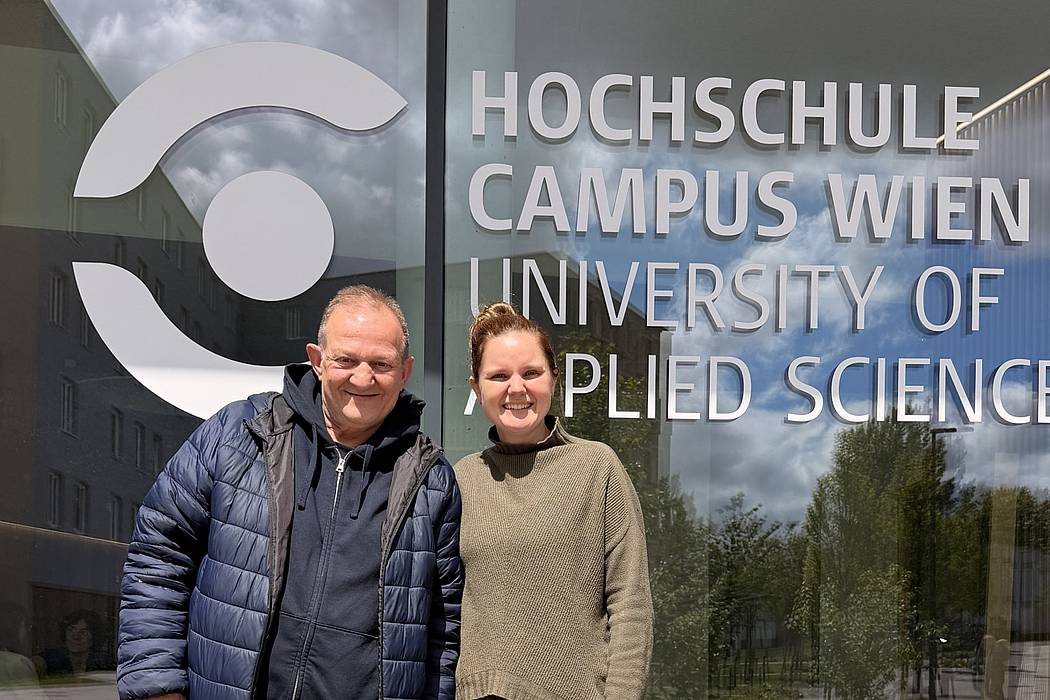 Eine weibliche und eine männlliche Person vor dem Logo der HCW