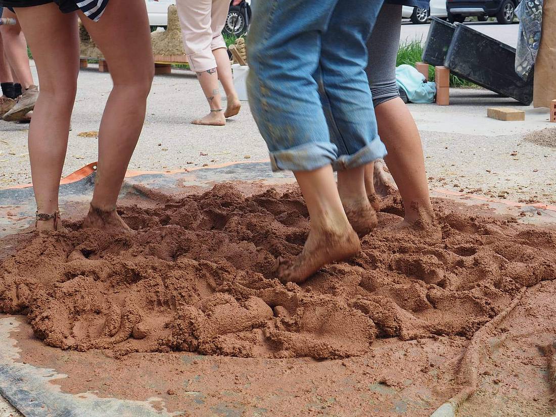 © HCW / Santana-Sosa Füße vermengen oder verdichten lehmähnliches Baumaterial