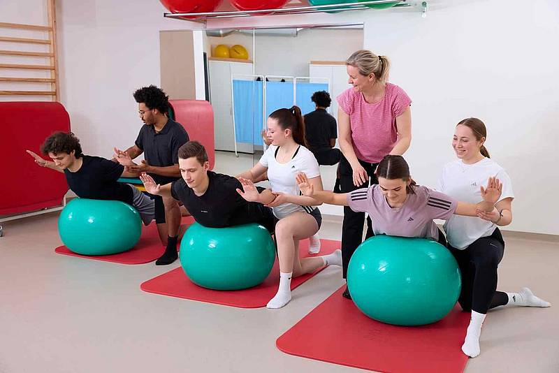 Studierende üben mit Patient*innen auf Therapiebällen