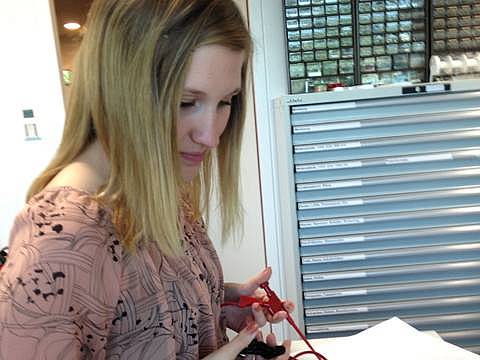 Schülerin häkt ein rotes und ein schwarzes Kabel in den Händen