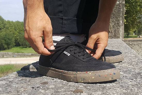 Foto © EFFEKT Footwear Mann bindet schwarzen Schuh aus Meeresplastik