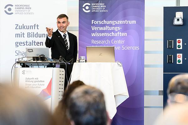 © HCW/Leitner Lehrender und Forschender Marlon Possard steht auf dem Podium und hält einen Vortrag
