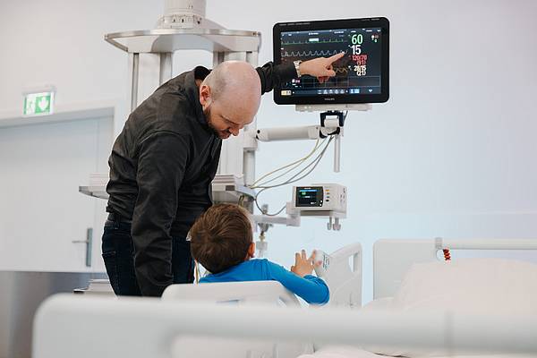 Vater und Sohn im OPIC der Hochschule Campus Wien, bei der Betrachtung eines technischen Geräts. 