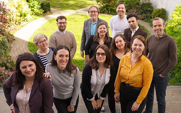 Eine Gruppe von 12 Menschen steht vor einer grünen Wiese