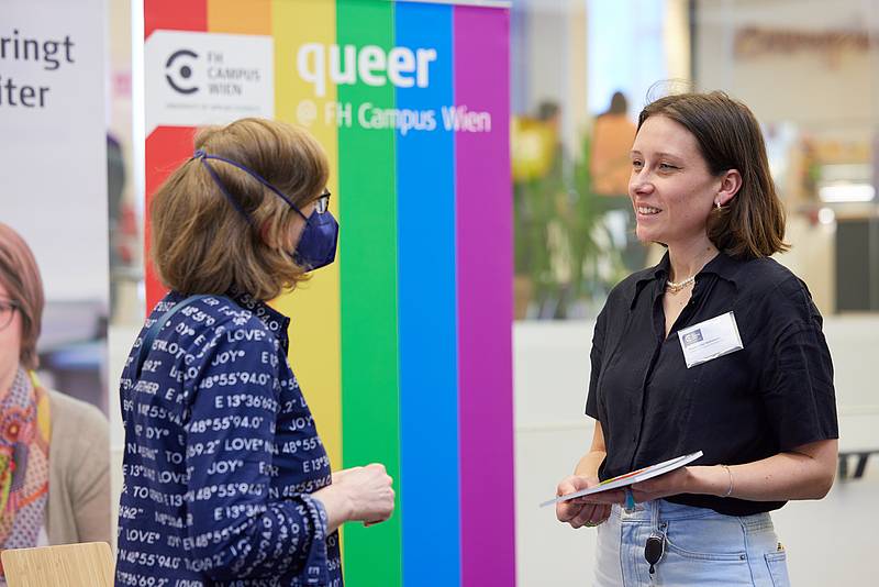 Eine Studierende berät eine Interessentin am Infostand zum Thema Diversität und Genderqueerness.