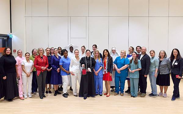 Gruppe von Personen, teils in historischen Dienstkleidungen von Gesundheits- und Krankenpflegepersonen - bereit für die Fashion Show 