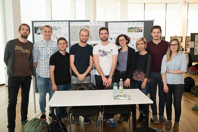 Gruppenfoto mit neun Personen, die hinter einem Tisch stehen