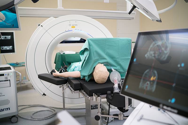 Medizinische Übungspuppe auf OP Tisch mit CT im Hintergrund