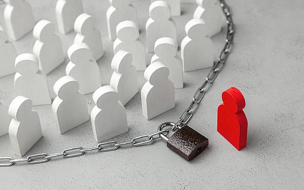 mehrere weiße Figuren stehen innerhalb einer abgeschlossenen Kette, außerhalb eine rote Figur