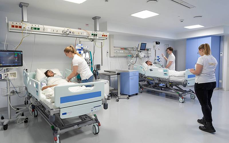 Studierende in einem Krankenzimmer mit zwei Patienten