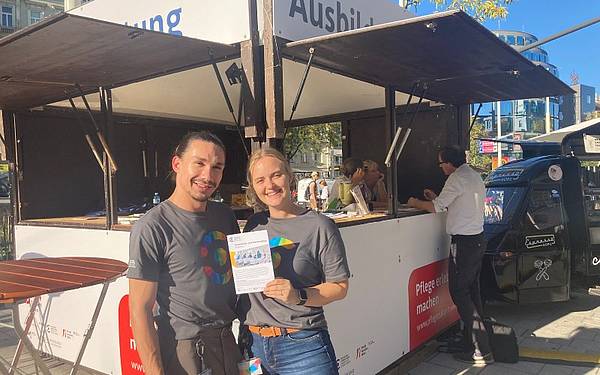 (c) Hochschule Campus Wien / Baumgartner 2Personen in TShirts der Hochschule Campus Wien vor einer Beratungshütte auf der Mariahilferstraße