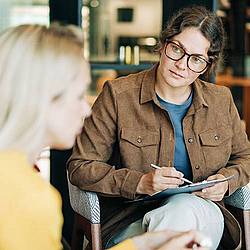 2 persons in conversation, one is taking notes
