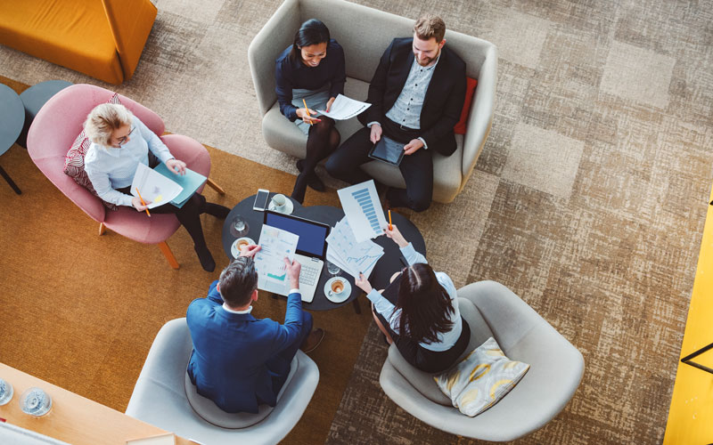 Eine Gruppe hat sich um einen Tisch versammelt und ist von Oben abgebildet