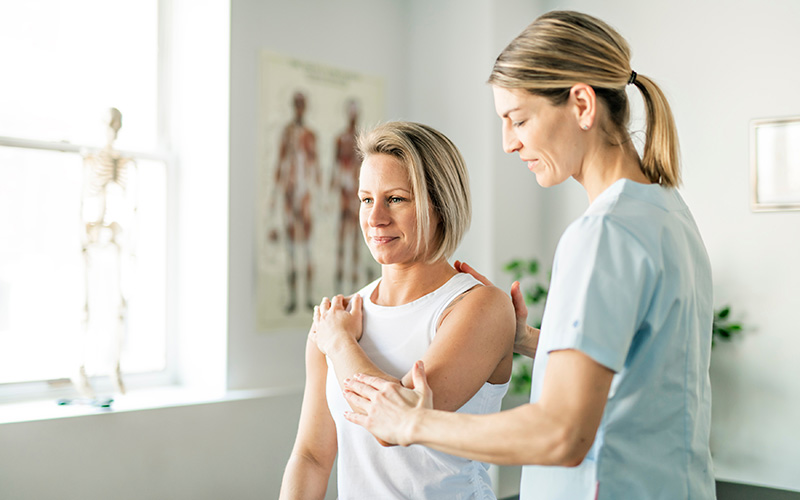 © Lopolo / Shutterstock.com Eine Physiotherapeutin unterstützt eine Patientin bei einer Beweglichkeitsübung ihrer Schulter