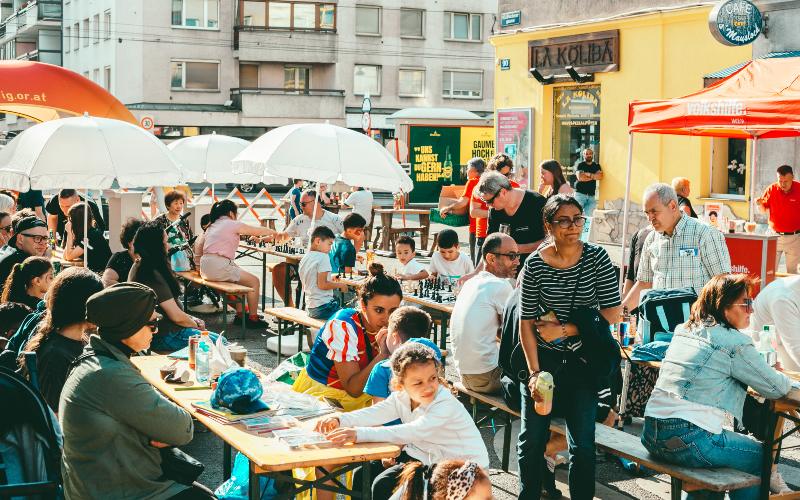Leute sitzen zusammen an Tischen in der Sonne
