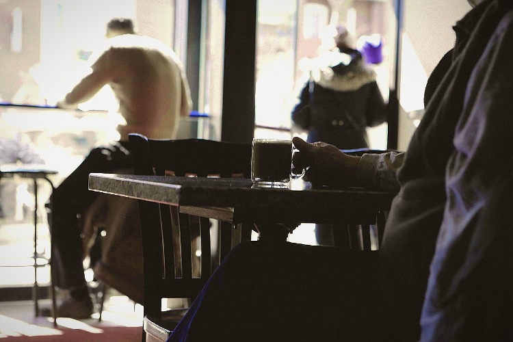3 Personen sitzen einzeln im Kaffeehaus, die Gesichter sind nicht erkennbar
