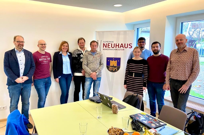 Gruppenbild in Besprechungsraum mit Rollup der Gemeinde Neuhaus