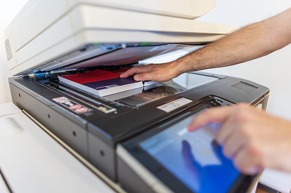 Ein aufgeklappter Kopierer mit einem aufgeschlagenen Buch auf der Kopierfläche.