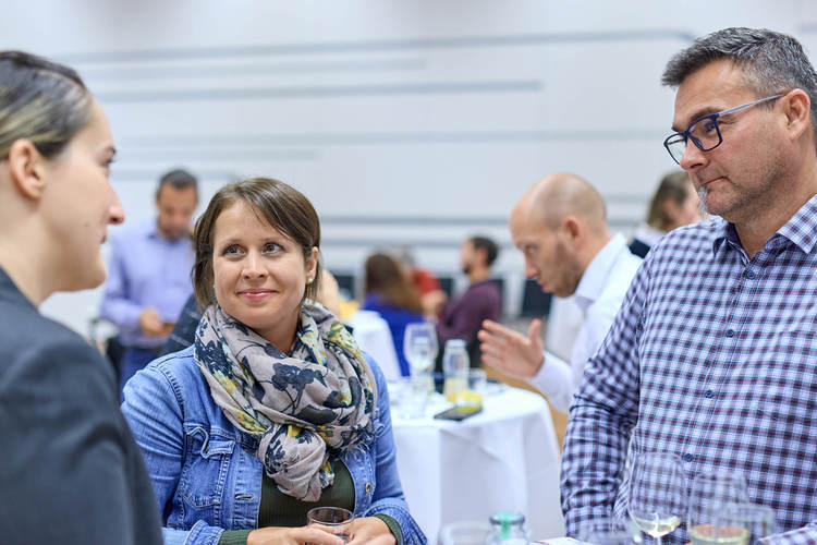 © HCW/Schedl 3 Absolvent*innen stehen am Tisch und reden miteinander