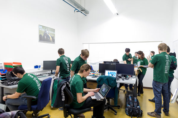 Eine Gruppe von Studenten und Studentinnen in grünen Shirts bei der Projektarbeit