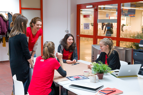 Sechs junge Frauen in roten Shirts bei Meeting