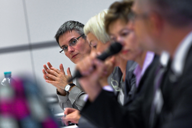 Four people pictured from the side, seated at a table.