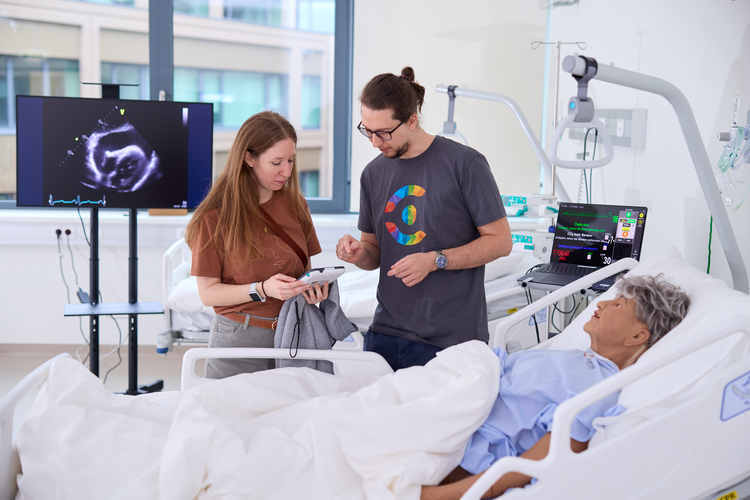 Eine Person der Hochschule Campus Wien erklärt Studieninteressierten etwas im Simulationszentrum, auch SimLab genannt.