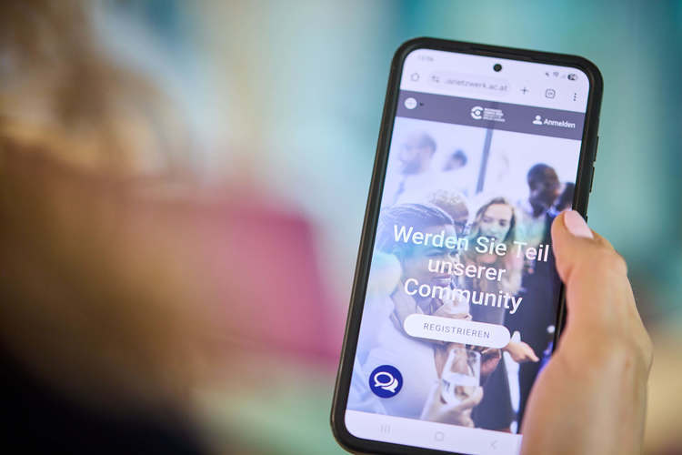 Person hält Handy in der Hand, auf dem Bildschirm sieht man die Startseite des Campusnetzwerks