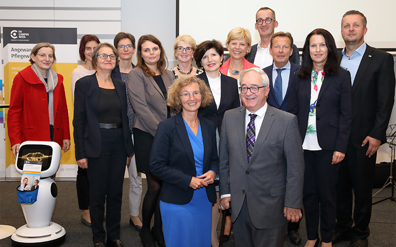 Gruppe von Männern und Frauen links davon eine Pflegeroboter