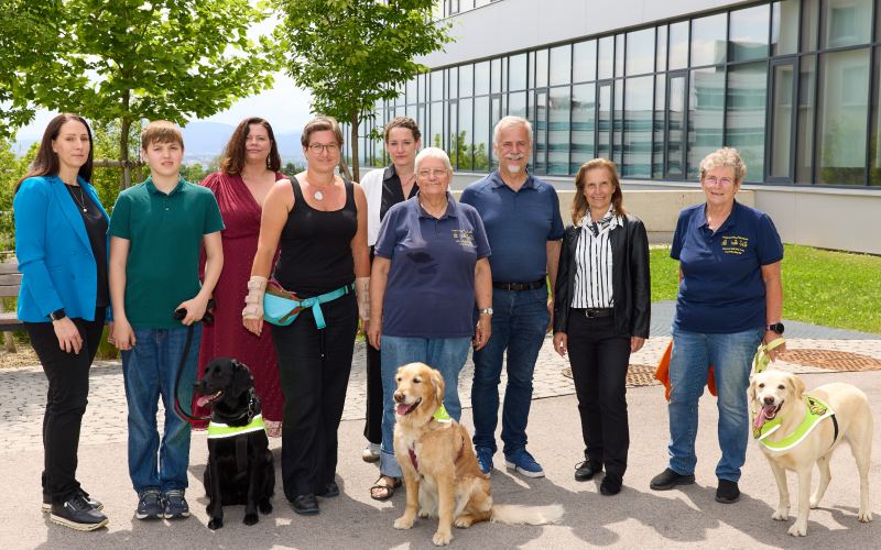 9 Personen und 3 Hunde vor dem Gebäude der Hochschule Campus Wien