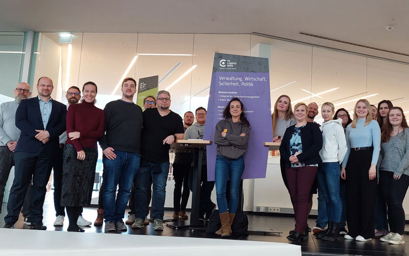 Studierende stehen als Gruppe vor Tisch