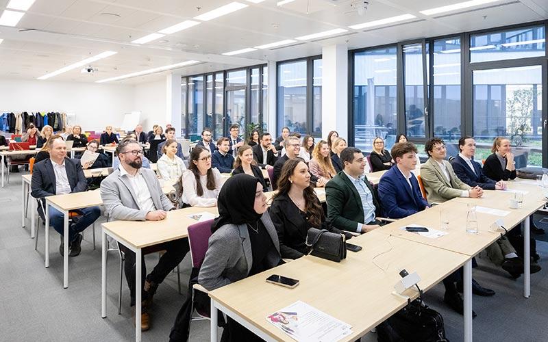 Studierende des Studienprogramms Tax Management sitzen im Raum und hören dem Vortragenden zu.