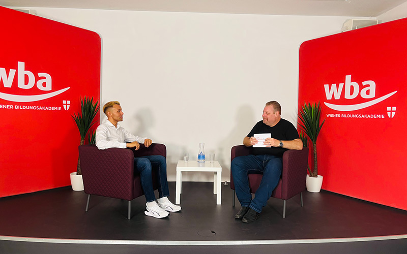Zwei Männer auf einem Podium sprechen miteinander