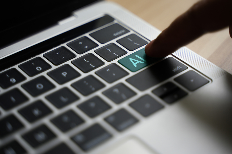© iStock/Sansert Sangsakawrat Laptoptastatur, ein menschlicher Finger drückt auf eine Taste, auf der AI steht