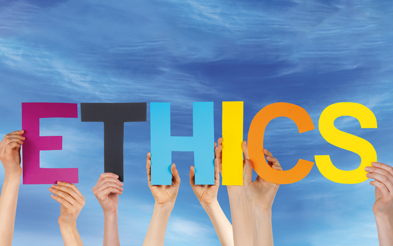 Händer verschiedenener Menschen halten bunte Buchstaben, die das Wort ETHICS ergeben geschrieben