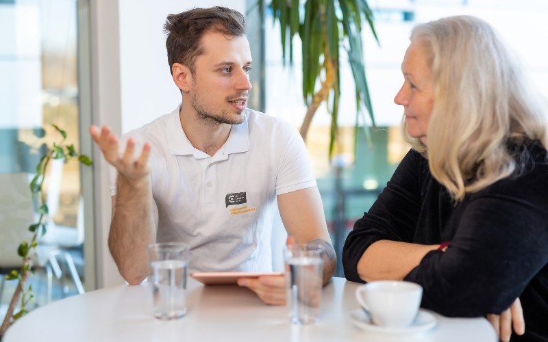 Junger mann mit älterer Frau an einem Tisch mit Getränken im Gespräch
