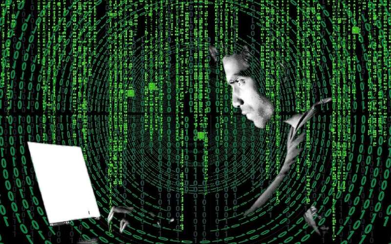 Mann sitzt vor Computer, davor transparent Programmiercode