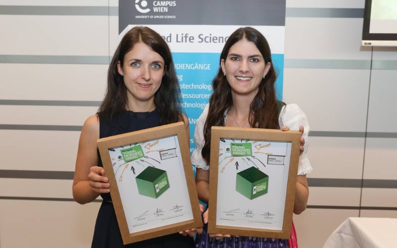 Die beiden Studierenden halten ihre Urkunde in den Händen